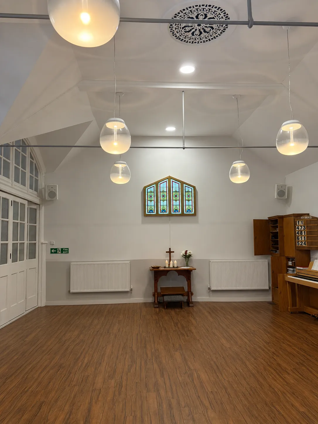 The church room cleared of chairs, facing the altar table and stained-glass window