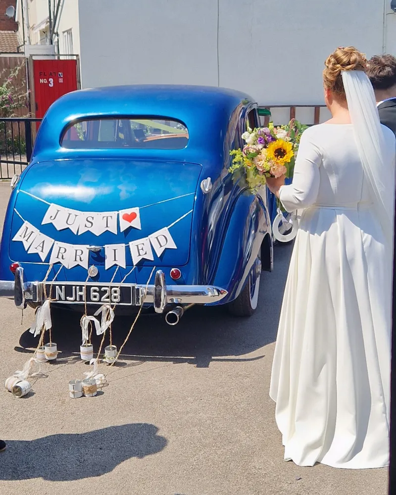 A wedding car decorated with a “Just Married” sign outside the church